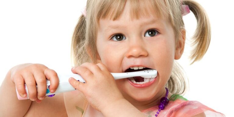 A smiling child brushing her teeth