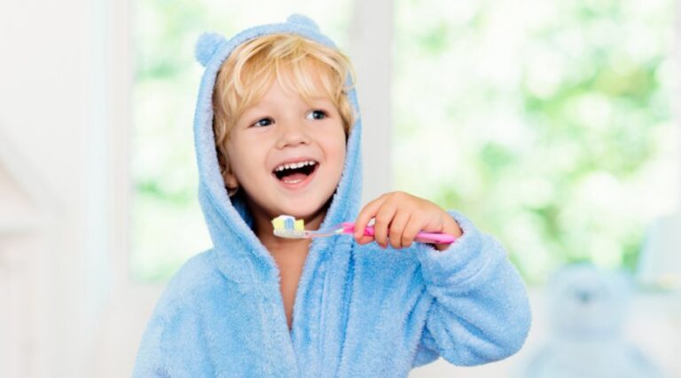 A smiling child brushing his teeth